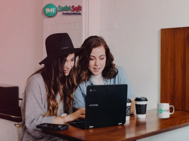 Two colleagues collaborating on a laptop in the SathiSoft office